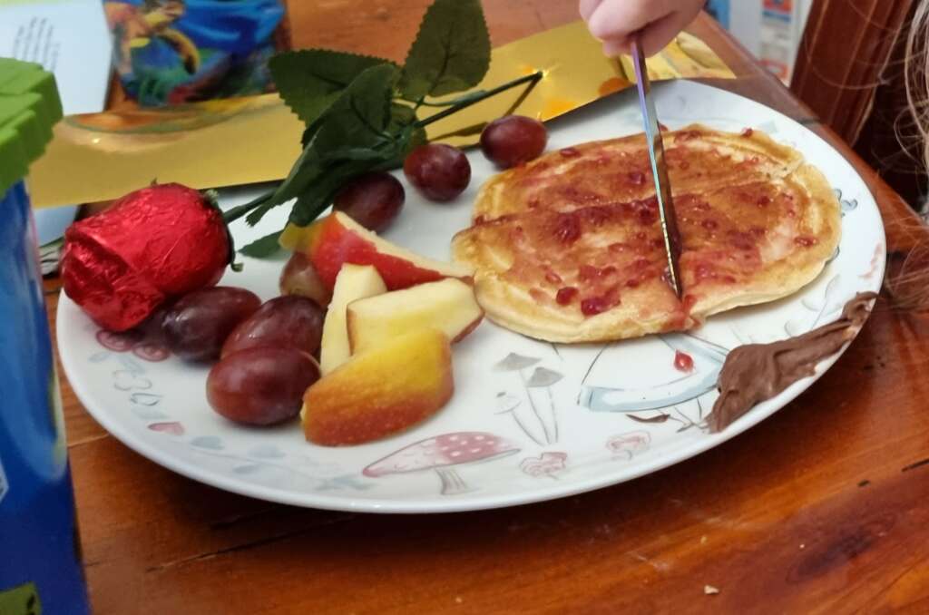 Pancakes with grapes, apples and a chocolate rose